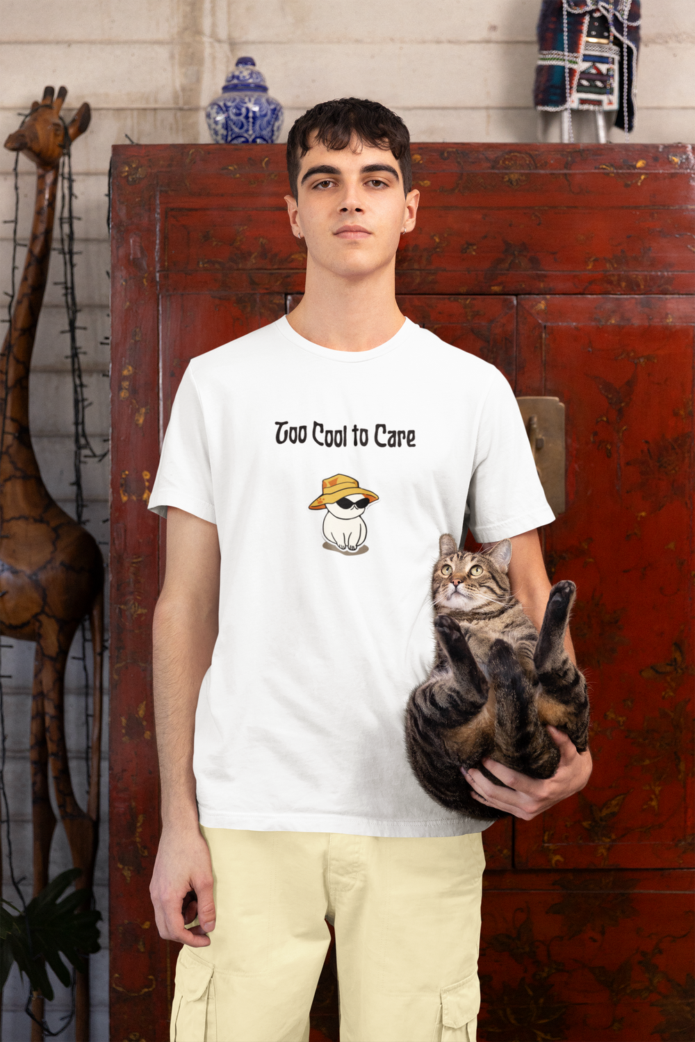 Man holding his cat, wearing the white Too Cool To Care tee